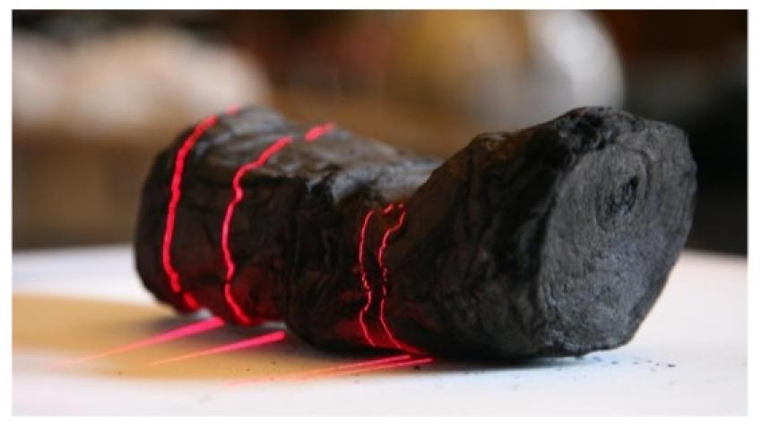 Herculaneum scroll with red laser lines being scanned at Institut de France by Brent Seales and his team.